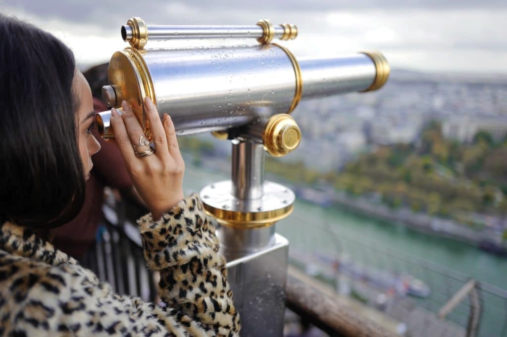 Une touriste qui admire la vue avec un télescope depuis la tour eiffel